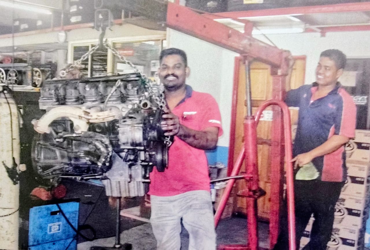 Kannan and a team member hoisting an engine